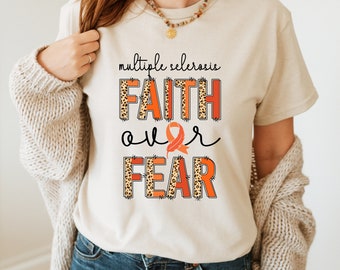May include: A beige t-shirt with the text "multiple sclerosis" and "FAITH over FEAR" in orange and black letters with a leopard print pattern. An orange ribbon is incorporated into the design.