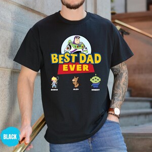 May include: Black crew neck t-shirt with the text "BEST DAD EVER" in yellow and red, featuring a Buzz Lightyear graphic and three character illustrations with names. A casual style.
