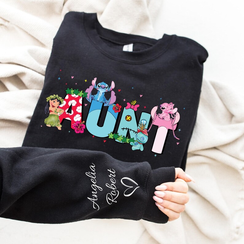 May include: Black sweatshirt with a colorful "AUNT" graphic featuring Stitch and Lilo characters. The sweatshirt has a personalized message on the sleeve that reads "Angelia Robert".