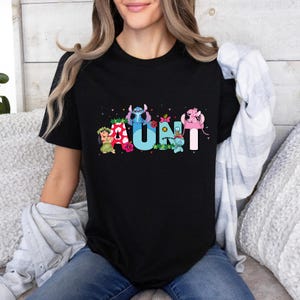 Puede incluir: Camiseta negra con un gr&aacute;fico de Stitch y otros personajes de Disney que deletrean "AUNT".