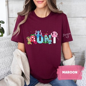 Puede incluir: Camiseta de color granate con un gr&aacute;fico de personajes de Stitch que deletrean "AUNT" con un coraz&oacute;n rosa y el nombre "Jessica" en la manga.