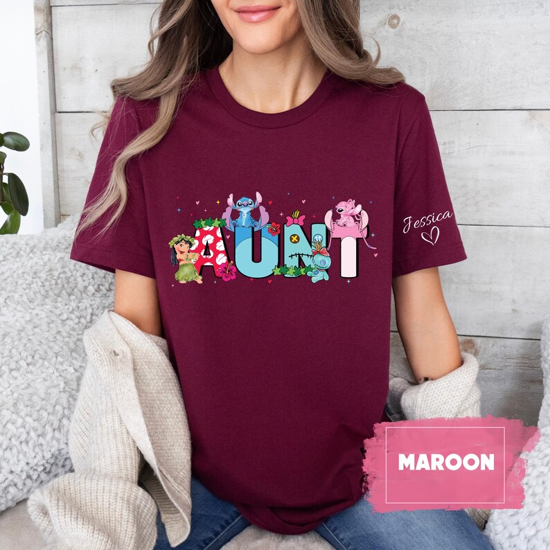 Puede incluir: Camiseta de color granate con un gr&aacute;fico de personajes de Stitch que deletrean "AUNT" con un coraz&oacute;n rosa y el nombre "Jessica" en la manga.