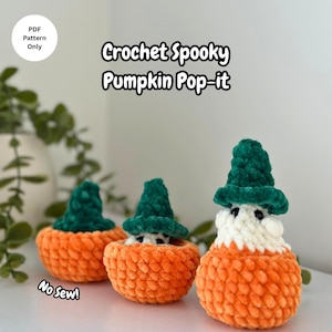 May include: Three handmade crochet pumpkin pop-its. Each pumpkin is orange with a green hat and a white face. The text on the image says "Crochet Spooky Pumpkin Pop-it" and "PDF Pattern Only" and "No Sew!"