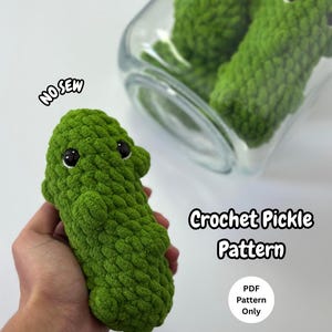 Könnte beinhalten: Eine grüne gehäkelte Gurke mit schwarzen Augen. Der Text "NO SEW" befindet sich über der Gurke. Das Bild enthält auch den Text "Crochet Pickle Pattern" und "PDF Pattern Only".