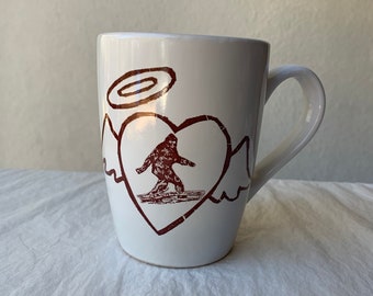 White Ceramic Big Foot/Sasquatch Surrounded By Heart and Angel Wings and Halo 12 oz coffee cup mug