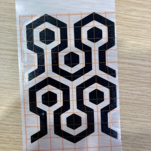 May include: Black and white geometric pattern with a repeating hexagonal design. The pattern is printed on a clear sheet with a grid.