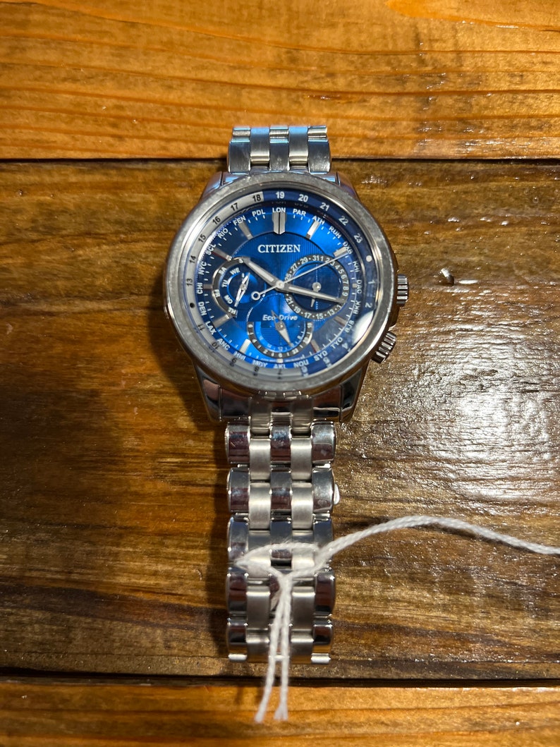 Pu&ograve; includere: Un orologio Citizen in acciaio inossidabile con quadrante blu. L'orologio presenta pi&ugrave; quadranti e lancette, con il marchio "CITIZEN" ben visibile. Anche il cinturino dell'orologio &egrave; in acciaio inossidabile.