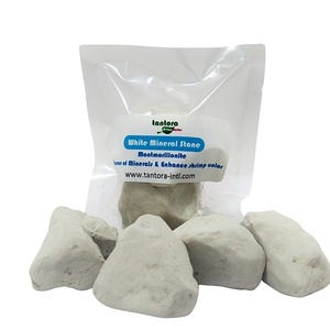 May include: White mineral stones in a clear plastic bag with the text "White Mineral Stone" and "Montmorillonite". Several loose stones are scattered around the bag. The stones are a light, off-white color.