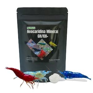 May include: A black pouch of Neocaridina Mineral GH/KH+ shrimp food with a colorful image of shrimp. A red, blue, and light blue shrimp are in front of the pouch, along with a spoonful of white powder.