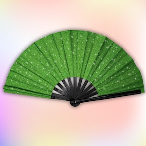 May include: A green glitter folding fan with a black handle. The fan is closed and the handle is visible.