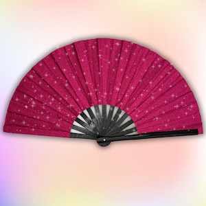 以下が含まれることがあります： 黒のハンドルとグリッターが付いたピンクのハンドファン。ファンは閉じられており、キラキラした仕上げになっています。