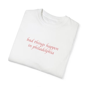 May include: White t-shirt with red text that reads "bad things happen in philadelphia"