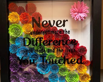 May include: A framed shadow box with a rainbow of paper flowers and the quote "Never underestimate the difference you made and the lives you touched".