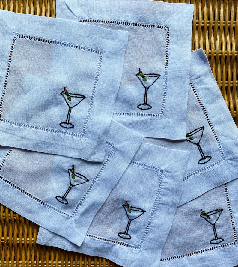 Peut inclure: Ensemble de six serviettes de cocktail en lin bleu avec des verres &agrave; martini et des olives brod&eacute;s. Les serviettes ont une bordure blanche et sont parfaites pour recevoir.
