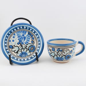 May include: A blue and white ceramic teacup and saucer set with a floral design. The set is hand-painted with blue and white flowers and leaves.