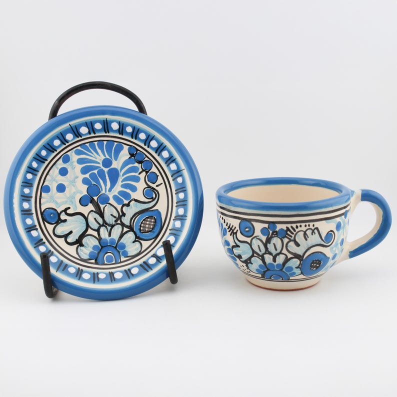 May include: A blue and white ceramic teacup and saucer set with a floral design. The set is hand-painted with blue and white flowers and leaves.