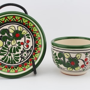 May include: A green and white ceramic teacup and saucer set with a floral design. The cup has a handle and the saucer has a rim.