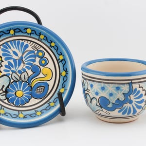 May include: A blue and white ceramic teacup and saucer set with a floral design. The cup has a handle and the saucer has a scalloped edge.