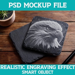 May include: Two dark grey slate coasters with a detailed engraving of an eagle's head. The coasters are on a wooden surface. The text "PSD MOCKUP FILE" and "REALISTIC ENGRAVING EFFECT SMART OBJECT" are visible.