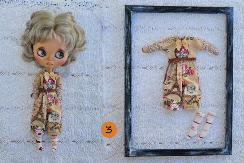 Puede incluir: Una mu&ntilde;eca de cabello rubio ondulado y ojos grandes viste un mono beige con estampado floral y de la Torre Eiffel, junto a un mono y calcetines a juego dentro de un marco rectangular negro, marcado con el n&uacute;mero 3 en un c&iacute;rculo naranja.