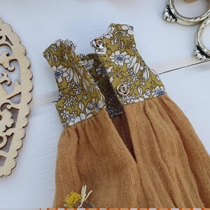 May include: A yellow and white floral print fabric doll dress with a mustard yellow skirt.