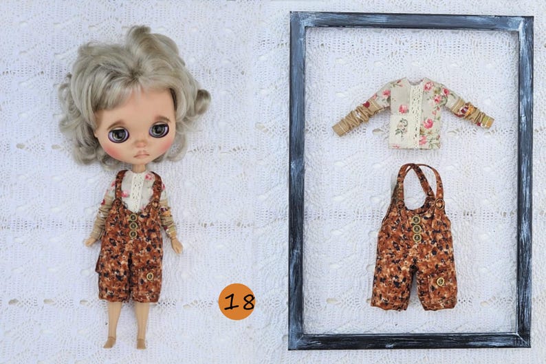 Puede incluir: Una mu&ntilde;eca de pelo rubio ondulado viste una camisa de flores de manga larga y un peto marr&oacute;n estampado con botones. Junto a la mu&ntilde;eca hay un marco negro que contiene una camisa de flores y un peto a juego con botones.