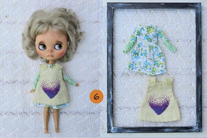Puede incluir: Una mu&ntilde;eca con cabello rubio ondulado viste un vestido sin mangas amarillo claro con un gr&aacute;fico de coraz&oacute;n morado sobre una camisa de manga larga con estampado floral verde y blanco, junto a un conjunto a juego dentro de un marco negro.