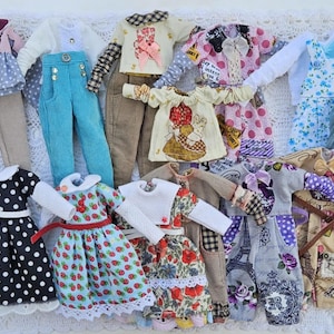 Puede incluir: Una colecci&oacute;n de ropa de mu&ntilde;eca en miniatura que incluye varios tops, pantalones, vestidos y petos con diversos estampados como lunares, fresas, motivos florales y la Torre Eiffel en una amplia gama de colores y texturas de tela.