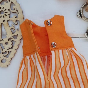May include: Orange and white striped dress with a solid orange bodice. The dress has two silver snaps on the back.