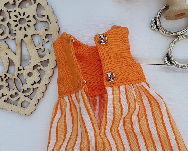 May include: Orange and white striped dress with a solid orange bodice. The dress has two silver snaps on the back.