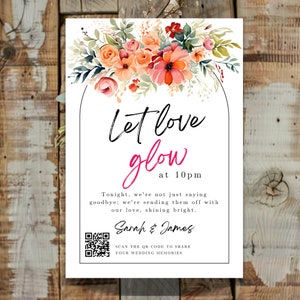 Puede incluir: Una tarjeta blanca con un diseño floral en la parte superior. El texto "Let love glow at 10pm" está escrito en negro y rosa. El texto "Tonight, we're not just saying goodbye; we're sending them off with our love, shining bright." está escrito en negro. El texto "Sarah & James" está escrito en negro. Un código QR se encuentra en la esquina inferior izquierda. El texto "SCAN THE QR CODE TO SHARE YOUR WEDDING MEMORIES" está escrito en negro.