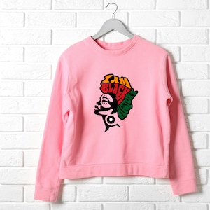 Può includere: Felpa rosa con una silhouette nera di una testa di donna con il testo "I AM BLACK HISTORY" in lettere colorate.