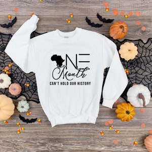 May include: White sweatshirt with a black graphic design featuring an outline of the continent of Africa and the text "ONE Month CAN'T HOLD OUR HISTORY".