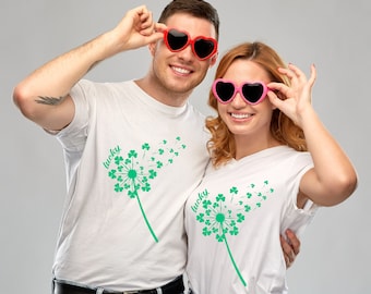 Puede incluir: Dos camisetas blancas con un diseño de diente de león de trébol verde y la palabra "lucky" en cada camiseta. La pareja lleva gafas de sol en forma de corazón.