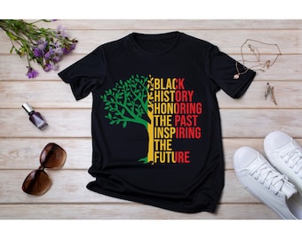 May include: Black t-shirt with a green and yellow tree design. The tree is made up of the words "Black History Honoring The Past Inspiring The Future".
