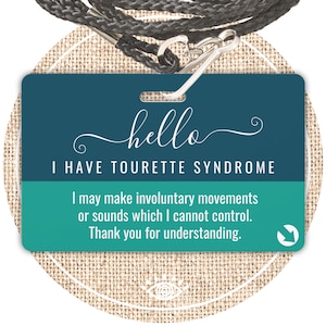 May include: A teal and white badge with the text "hello I HAVE TOURETTE SYNDROME". The badge also states "I may make involuntary movements or sounds which I cannot control. Thank you for understanding." A black lanyard with a metal clasp is attached.