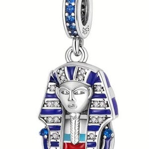 May include: Silver charm with a blue and white enamel depiction of an Egyptian pharaoh's head, with red and turquoise accents. The charm has a blue crystal ring around the top.