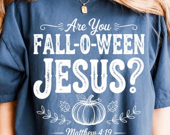 May include: A navy blue t-shirt with the text "Are You FALL-O-WEEN JESUS?" in white. A white pumpkin and leaf design is below the text, with "Matthew 4:19" underneath. The shirt is a casual, short-sleeved style.