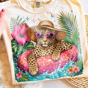 Sommarleopard PNG, tropisk geparddesign PNG, sublimering av strandsemester, trendig rosa poolmadrassgrafik, söt sommartröja PNG, rolig