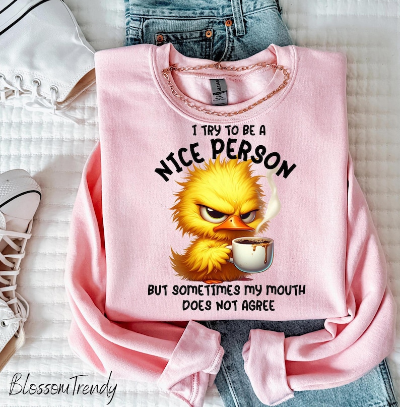 Pu&ograve; includere: Felpa rosa con un pulcino dei cartoni animati che tiene una tazza di caff&egrave;. Il testo sulla felpa recita "Cerco di essere una persona gentile, ma a volte la mia bocca non &egrave; d'accordo."