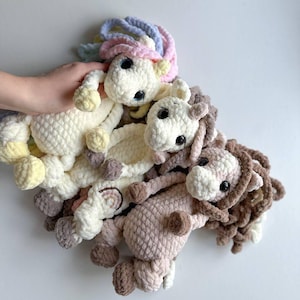 Puede incluir: Cuatro juguetes de peluche de unicornio tejidos a crochet en varios colores, incluyendo blanco, rosa, marrón y amarillo. Los juguetes tienen ojos grandes y están hechos con un hilo suave y esponjoso.