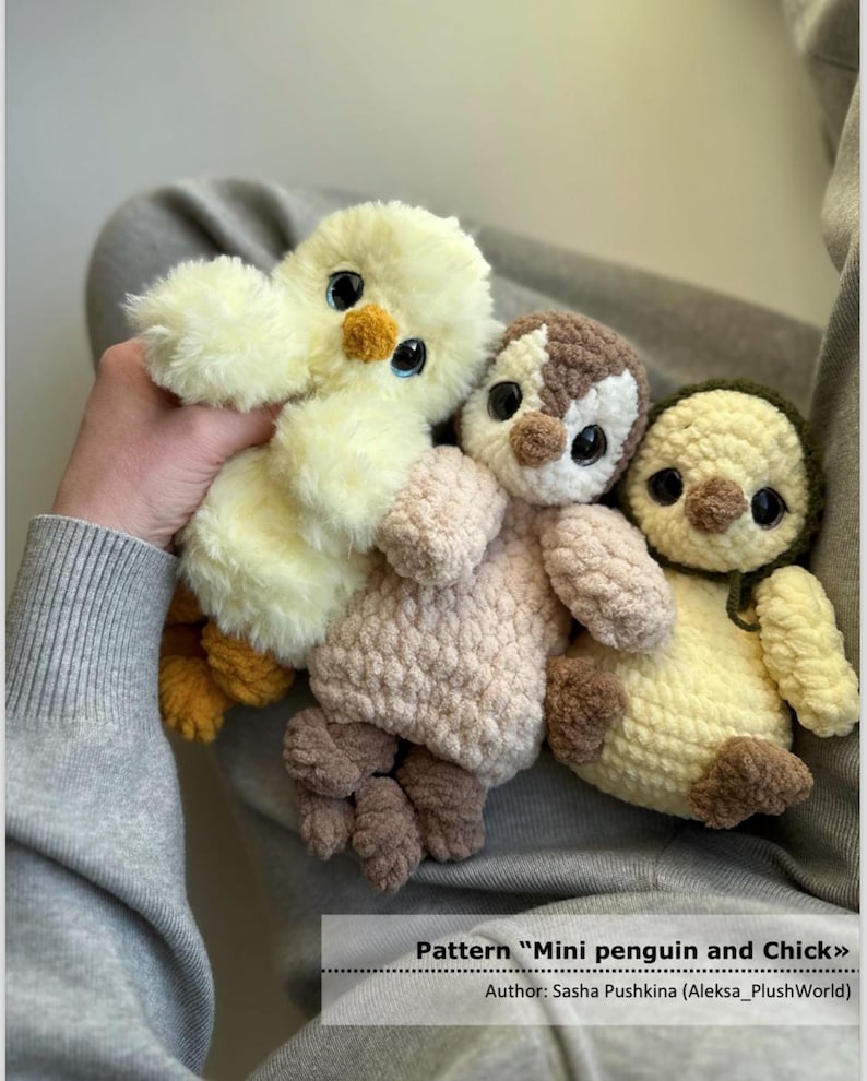 May include: Three plush toys featuring a fluffy yellow chick, a brown and white penguin, and a cream-colored bird with a dark green hood. Each toy has large black eyes and textured yarn bodies. The text reads: Pattern "Mini penguin and Chick" Author: Sasha Pushkina (Aleksa_PlushWorld).