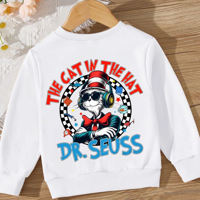 Peut inclure: Sweat-shirt blanc avec un graphique color&eacute; du Chat dans le Chapeau portant un casque et des lunettes de soleil. Le texte "The Cat in the Hat" et "Dr. Seuss" est imprim&eacute; sur le sweat-shirt.