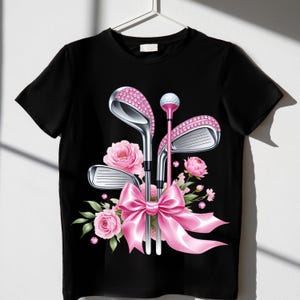 May include: Black t-shirt with a pink bow and three golf clubs with pink rhinestones. The clubs are surrounded by pink flowers.