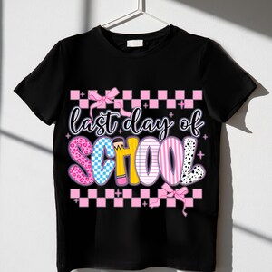 Puede incluir: Camiseta negra con un patr&oacute;n de cuadros rosa y blanco, un lazo rosa y el texto "&uacute;ltimo d&iacute;a de escuela" en letras de colores con un gr&aacute;fico de l&aacute;piz.