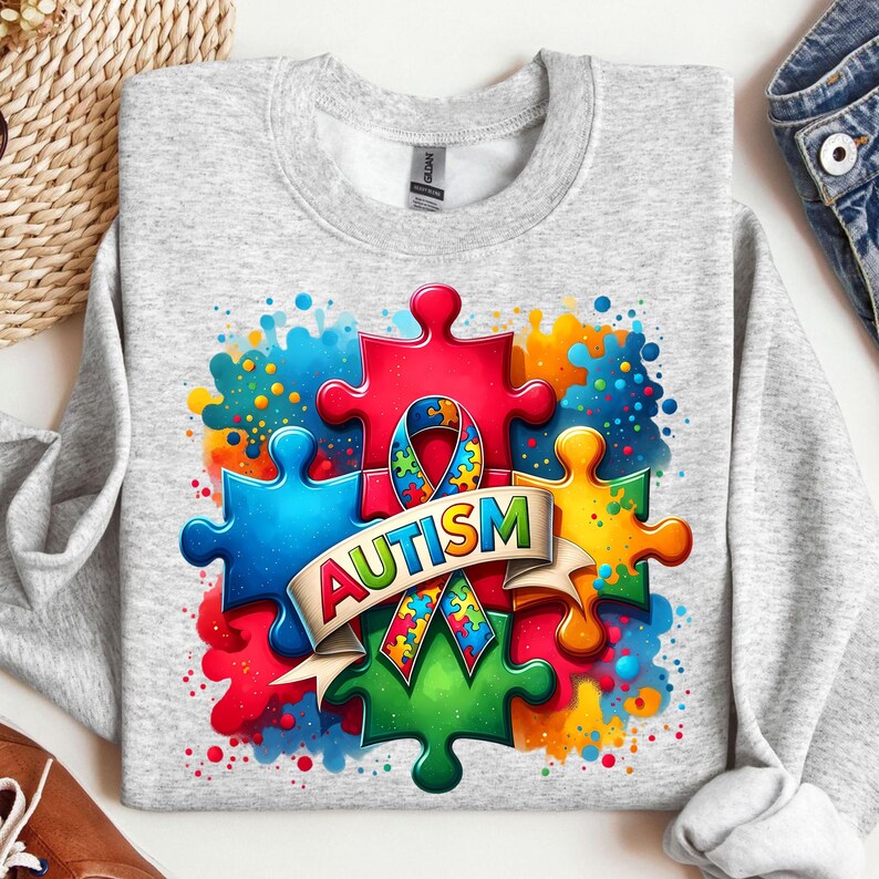 May include: A gray sweatshirt with a colorful design of puzzle pieces and a ribbon. The text "AUTISM" is written on a banner.