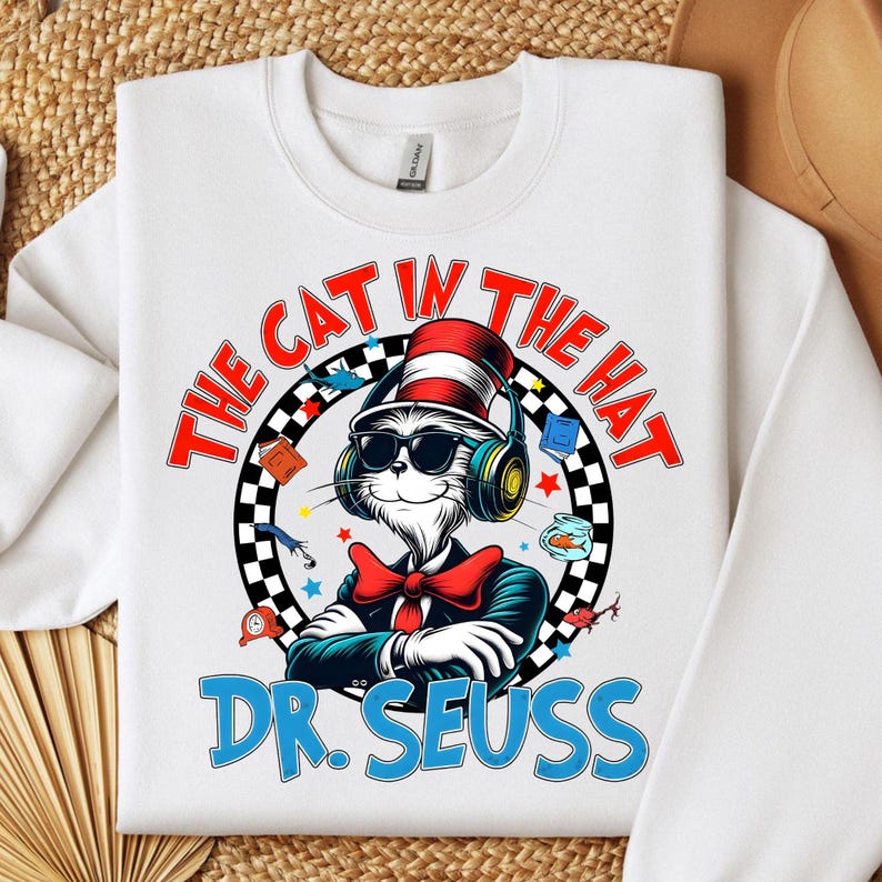 Peut inclure: Sweat-shirt blanc avec un graphisme color&eacute; du Chat dans le Chapeau portant un casque et un n&oelig;ud papillon rouge. Le texte "The Cat in the Hat" est dans un cercle rouge avec un motif &agrave; carreaux noir et blanc. Le texte "Dr. Seuss" est en bleu sous le graphisme.