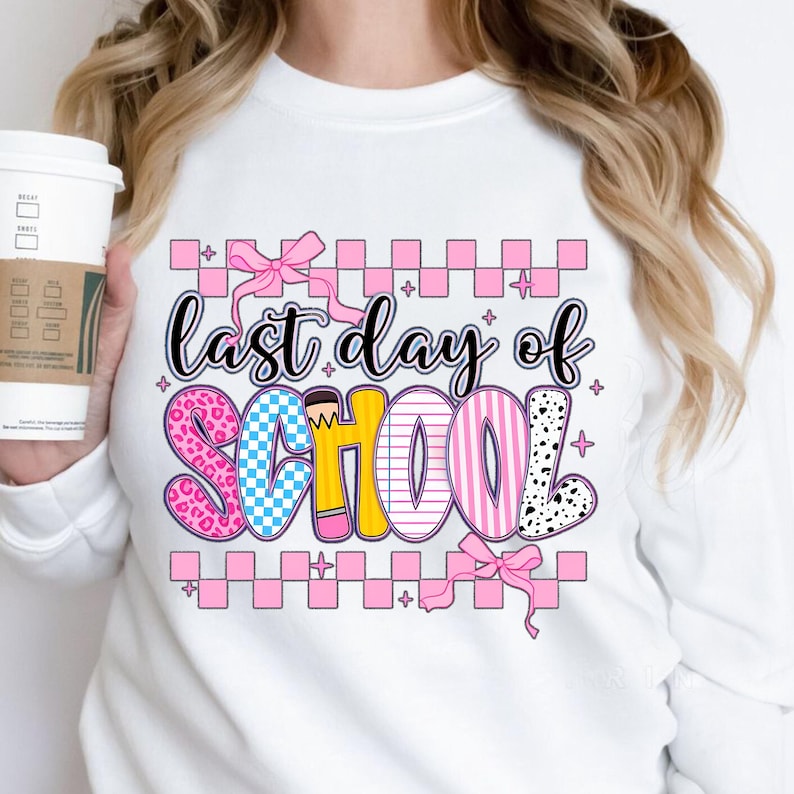 Puede incluir: Sudadera blanca con un gr&aacute;fico rosa, azul, amarillo y negro que dice "&uacute;ltimo d&iacute;a de escuela" con un lazo rosa y un patr&oacute;n a cuadros.