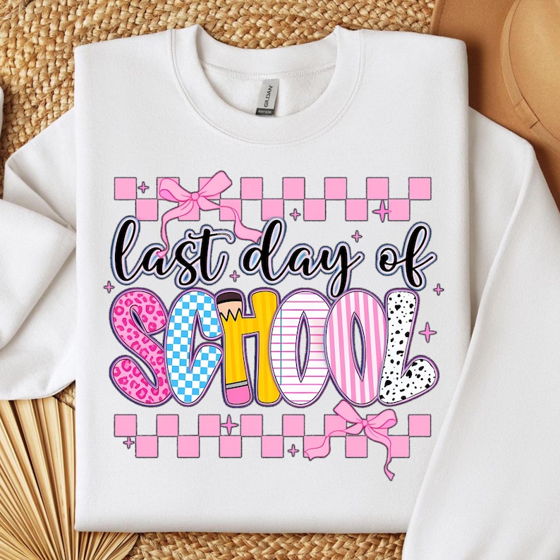 Puede incluir: Sudadera blanca con un gr&aacute;fico rosa, amarillo, azul y negro que dice "&uacute;ltimo d&iacute;a de escuela". El gr&aacute;fico est&aacute; decorado con un lazo, lunares y un patr&oacute;n a cuadros.