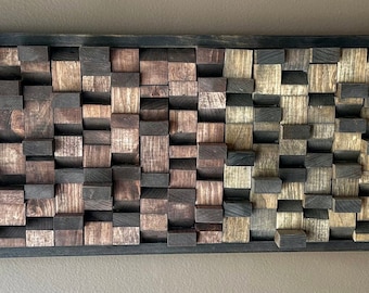 May include: A rectangular wall art piece made of wood blocks in various shades of brown, black, and natural wood. The blocks are arranged in a random pattern, creating a textured and visually interesting design.